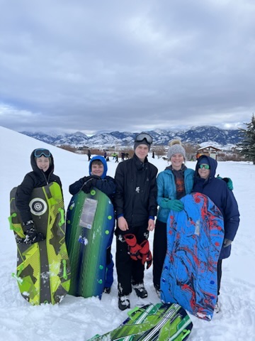 Youth group bundled up with sleds in the snow with the Bridger Mountains in the background