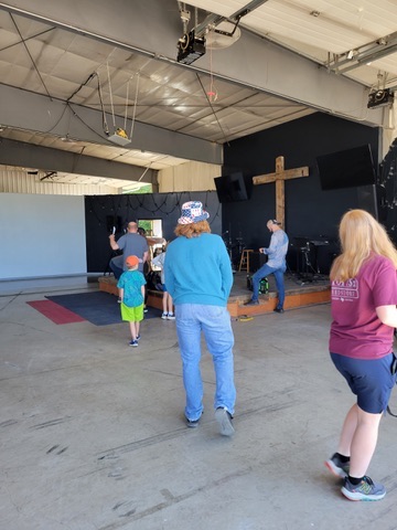 The stage and wooden cross at Gallatin River Fellowship as people gather before a service