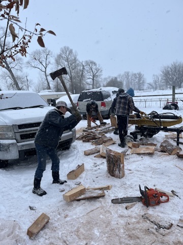 Men from the church cutting and splitting firewood in the snow to serve neighbors in need